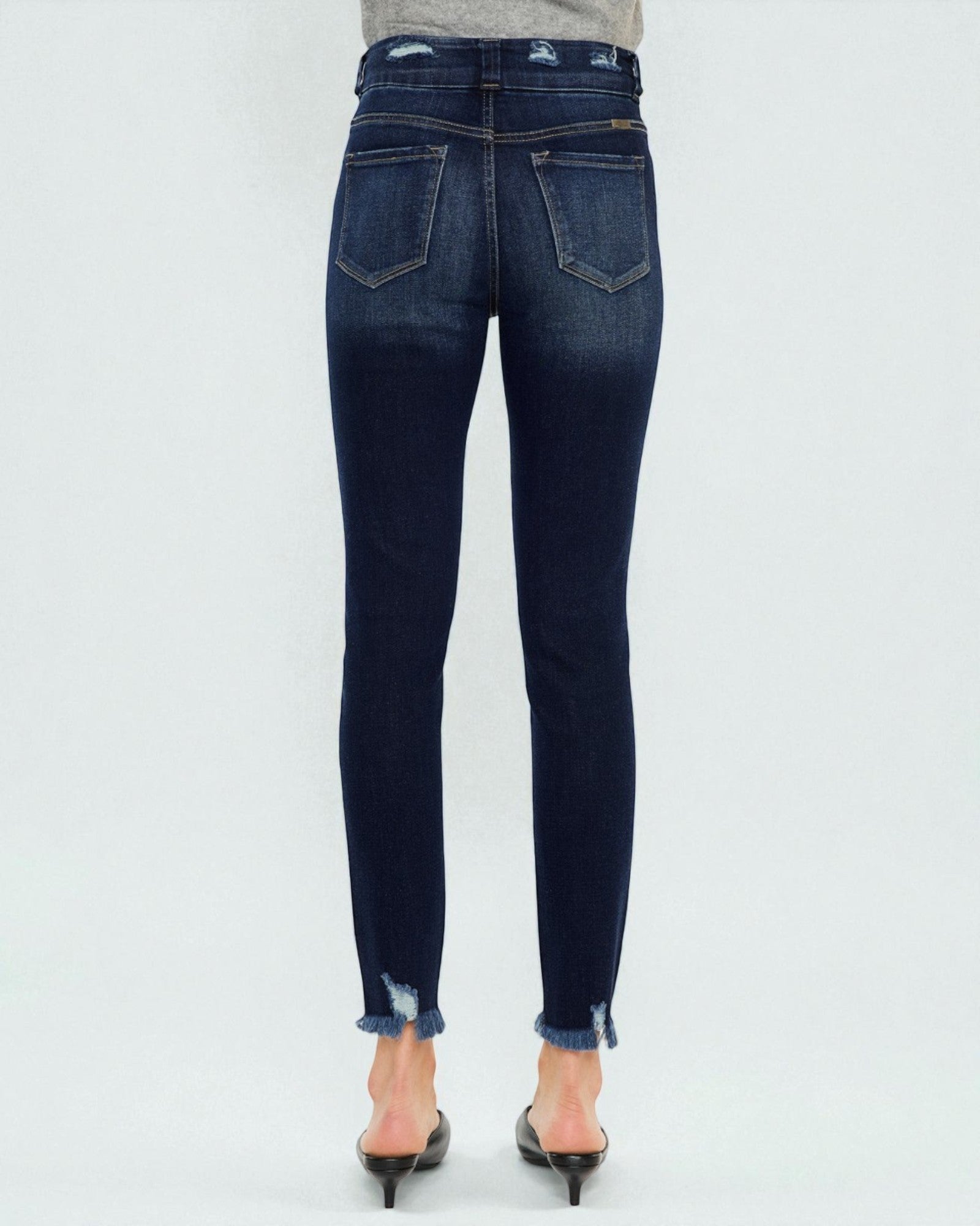 Dark blue jeans worn by a person on a white background