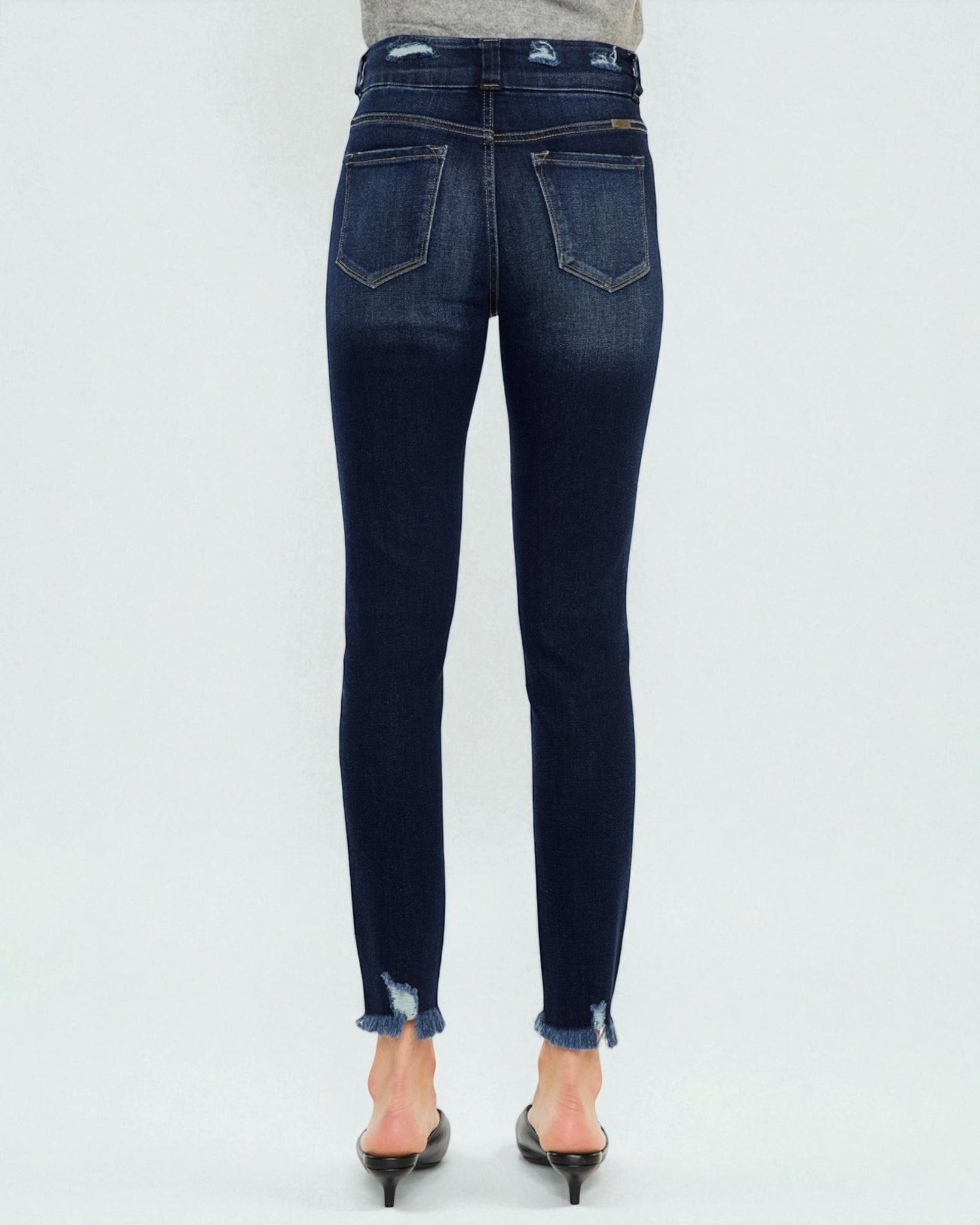 Dark blue jeans worn by a person on a white background