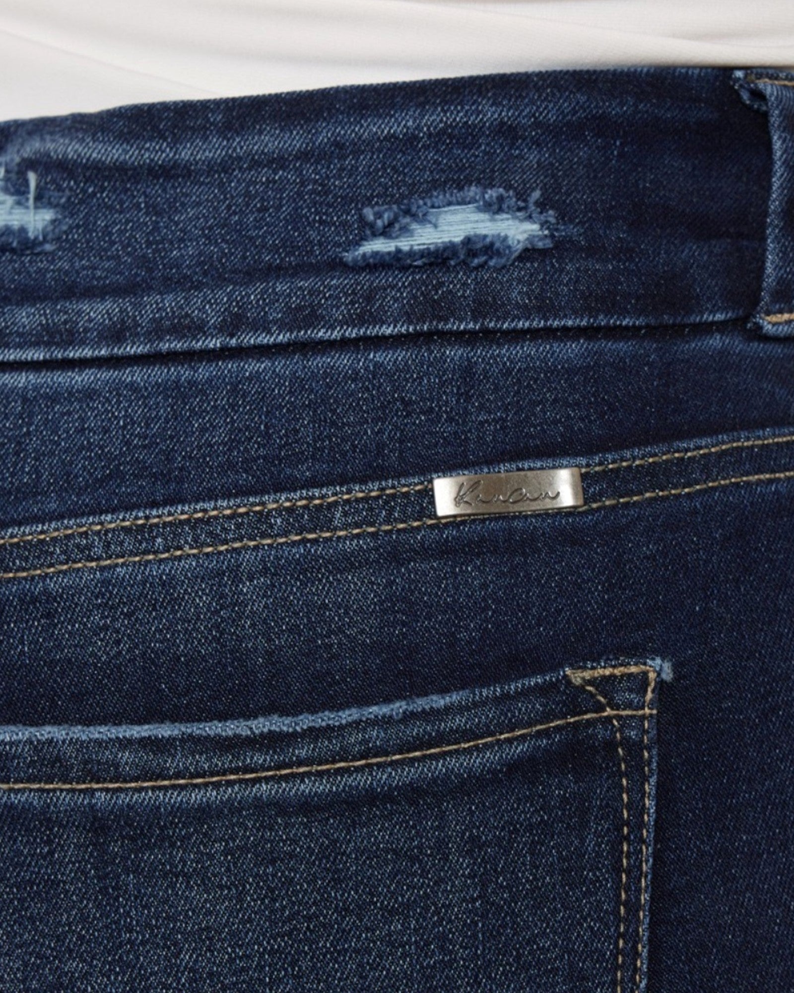 Close-up of dark blue jeans with a brand logo on the back pocket.