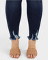 Navy blue distressed jeans worn with tan woven sandals on a white background