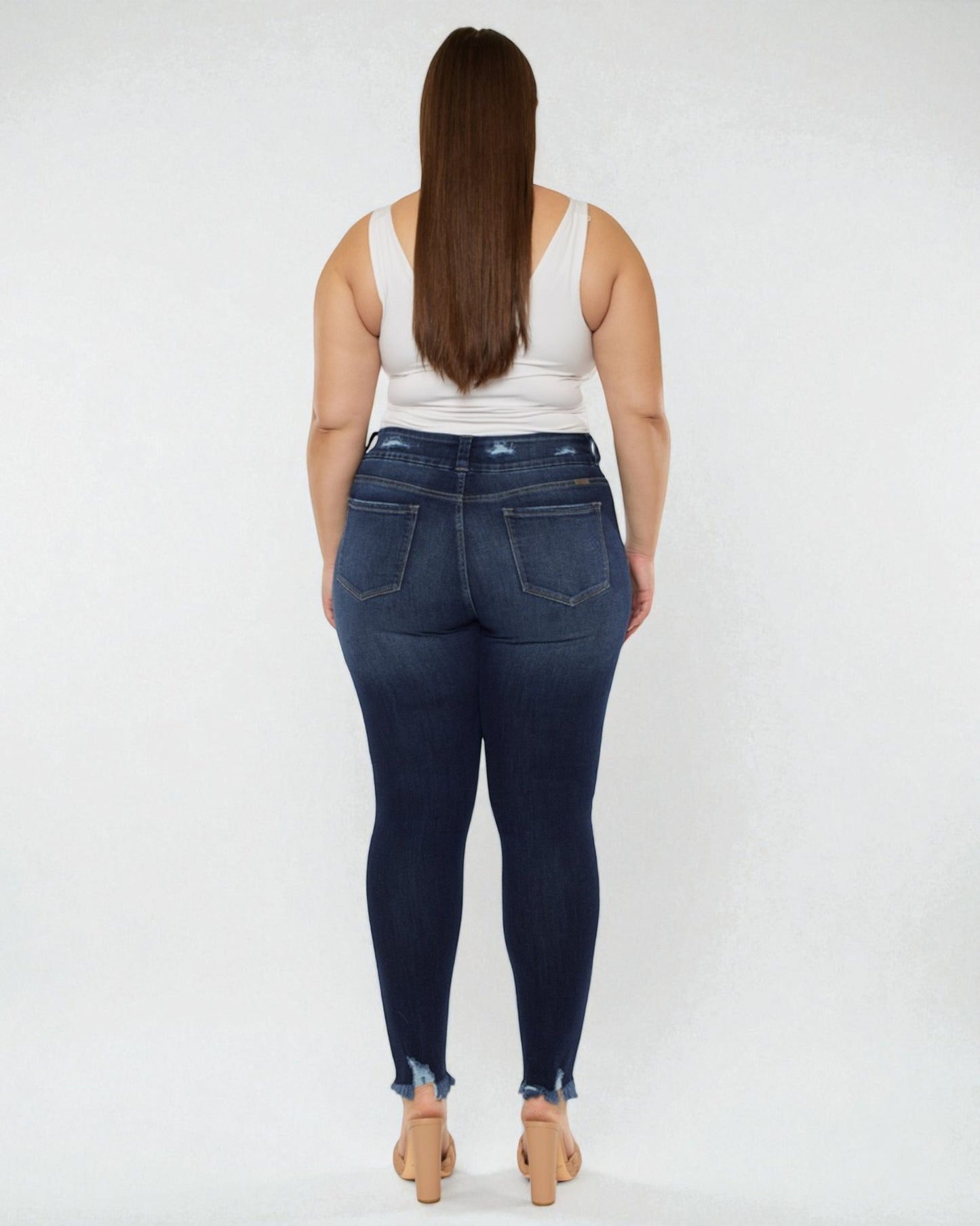 Person wearing dark blue jeans and a white tank top on a white background