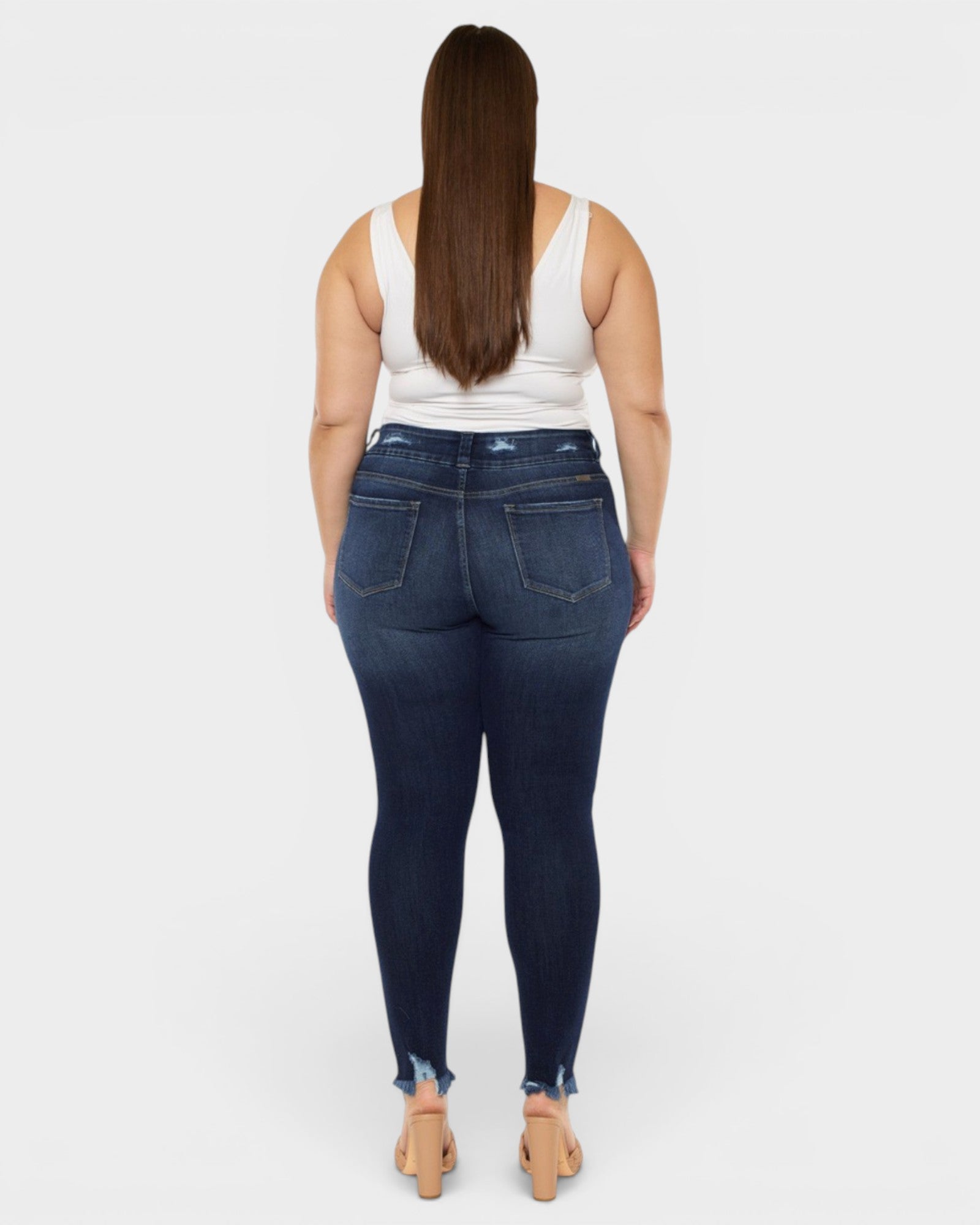 Person wearing dark blue jeans and a white tank top on a white background