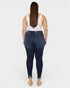 Person wearing dark blue jeans and a white tank top on a white background