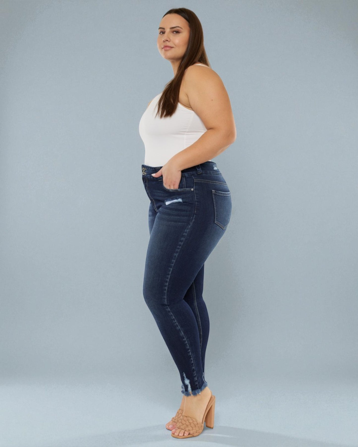 Woman wearing blue jeans and a white top on a gray background