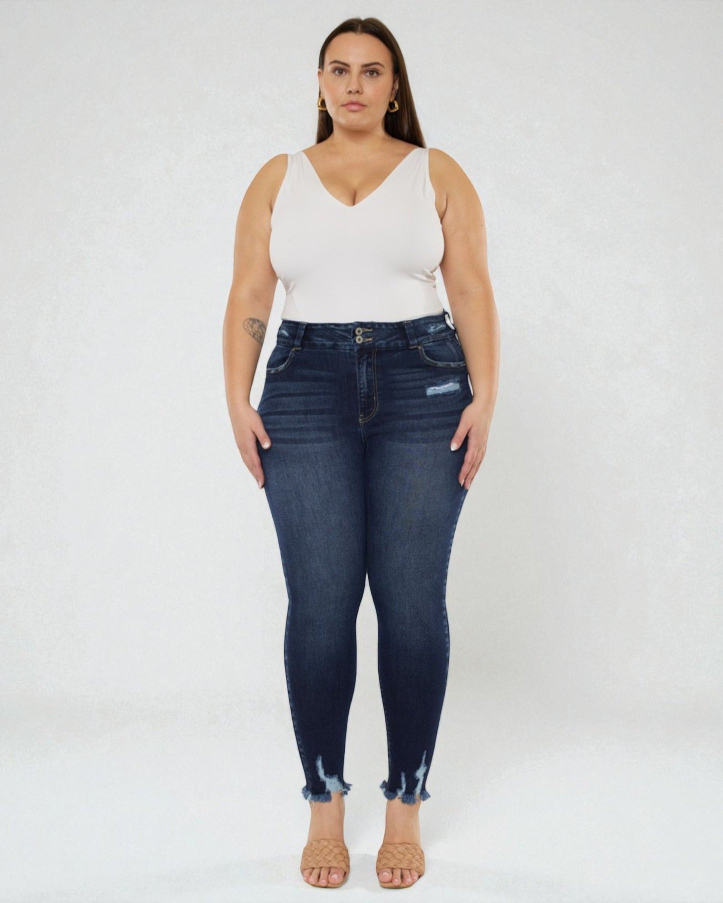 Woman wearing dark blue jeans and a white top on a white background