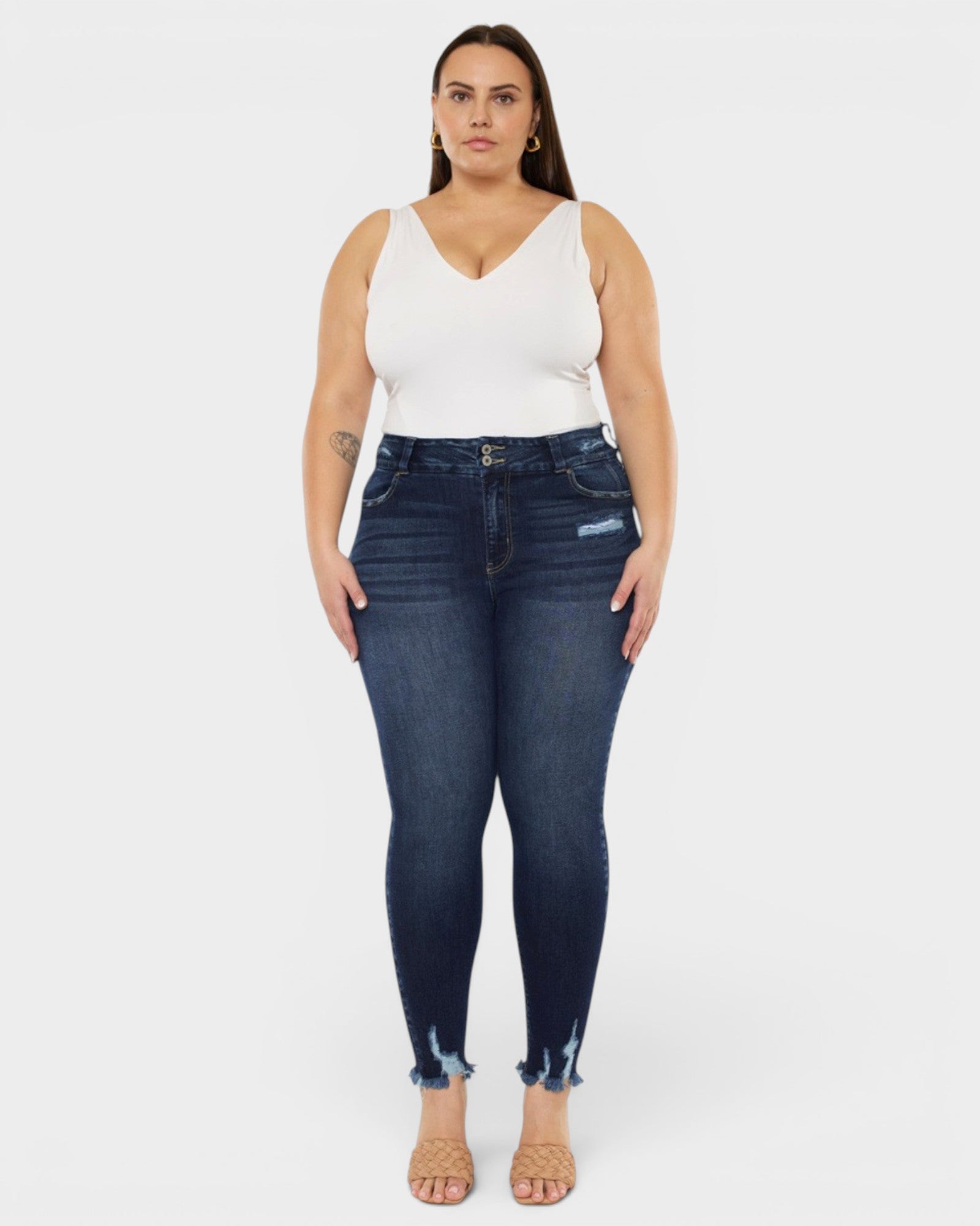 Woman wearing dark blue jeans and a white top on a white background