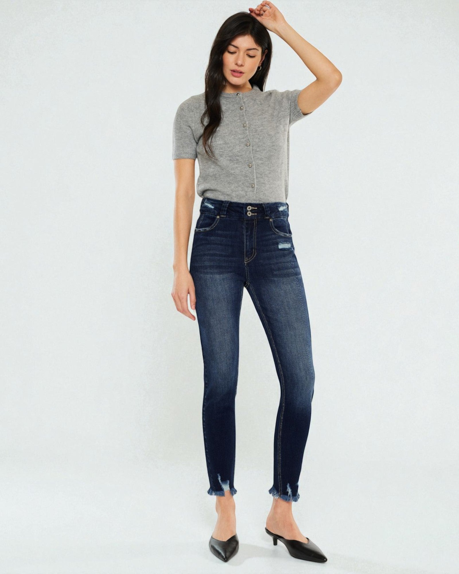Woman wearing a gray sweater and dark blue jeans on a white background