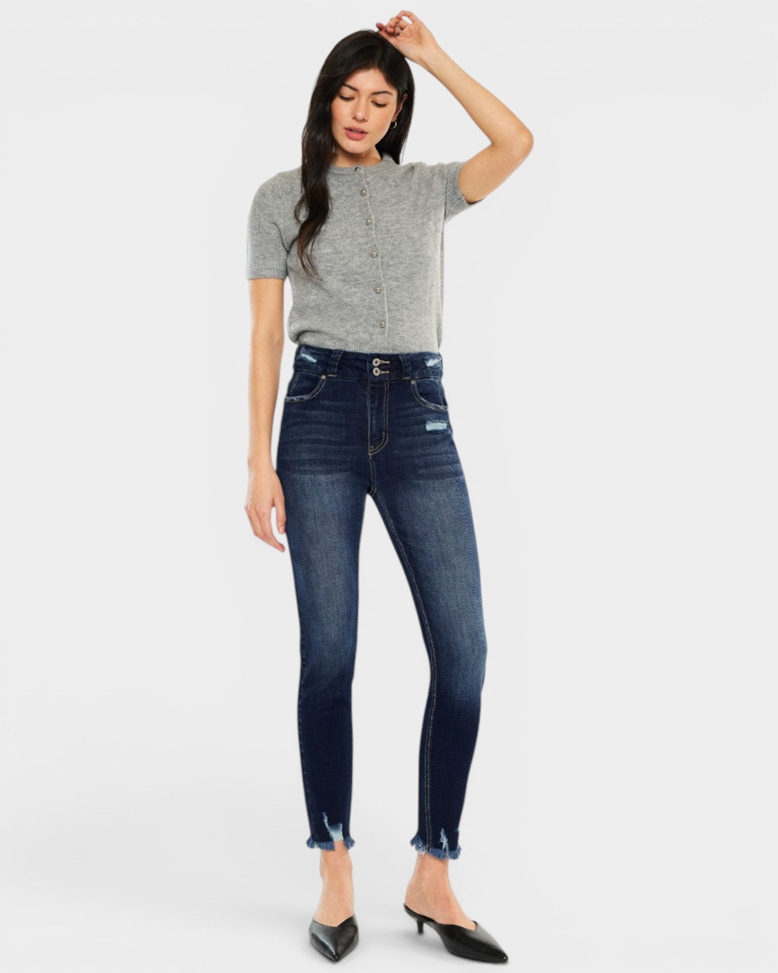 Woman wearing dark blue jeans and a gray top on a white background