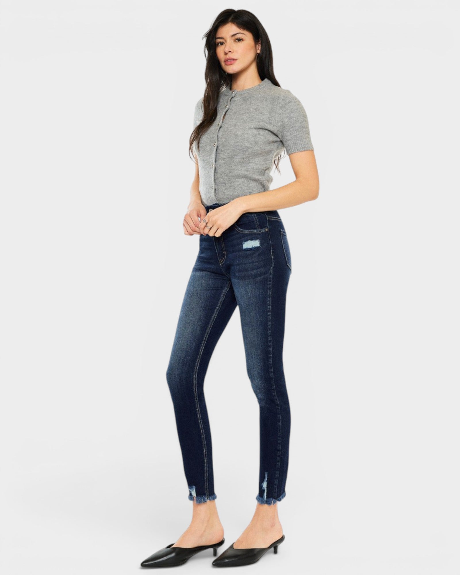 Woman wearing a gray top and blue jeans on a white background