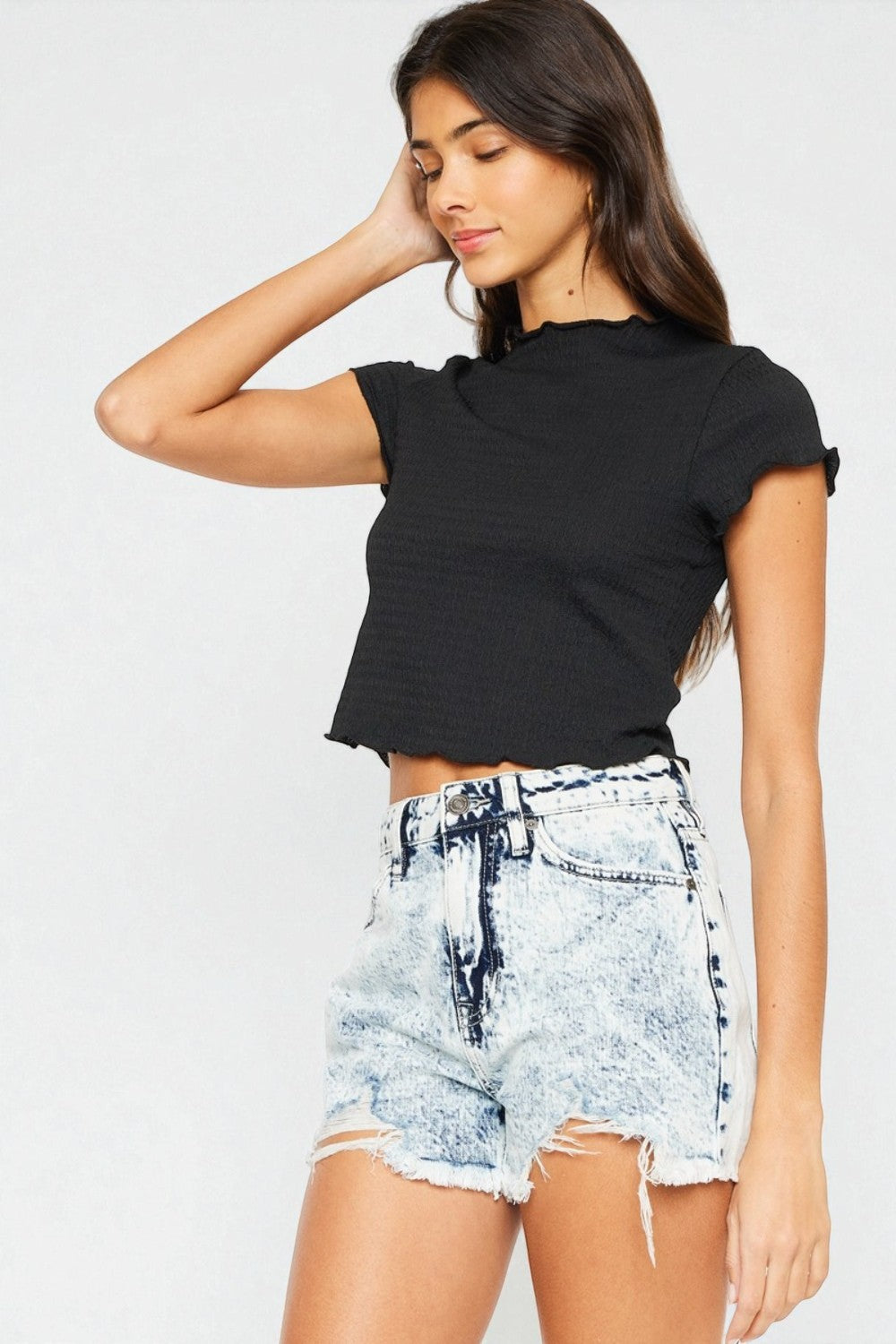 Woman wearing a black crop top and tie-dye shorts on a white background