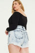 Woman wearing a black off-shoulder top and light blue denim skirt on a white background
