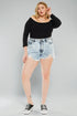 Woman wearing a black top and denim shorts on a gray background