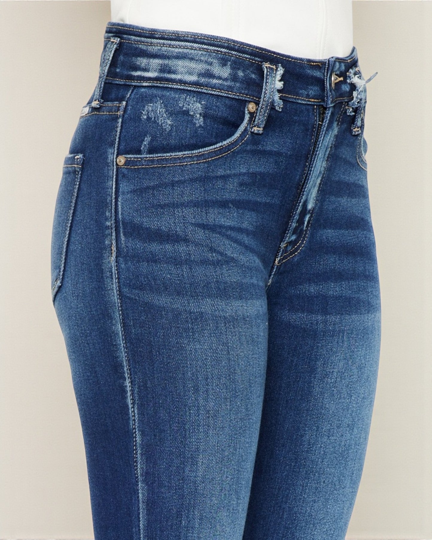Blue jeans with distressed details on a plain background