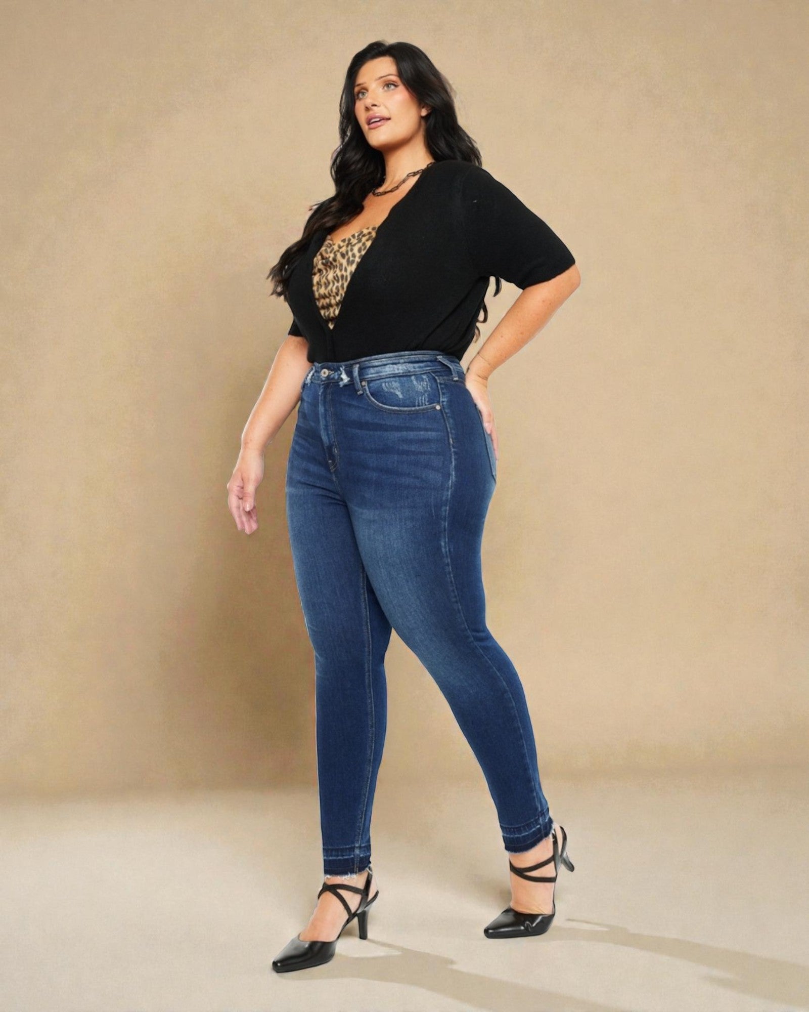 Woman wearing blue jeans and a black top with a leopard print design on a beige background