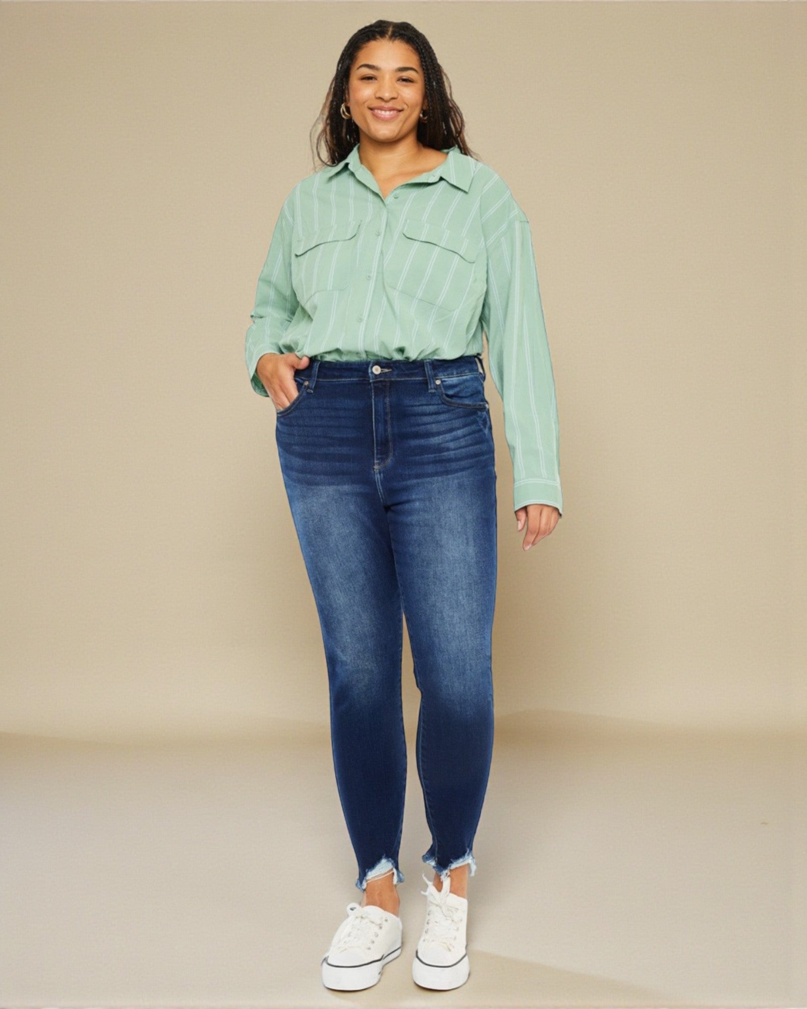 Woman wearing a light green shirt and blue jeans against a beige background