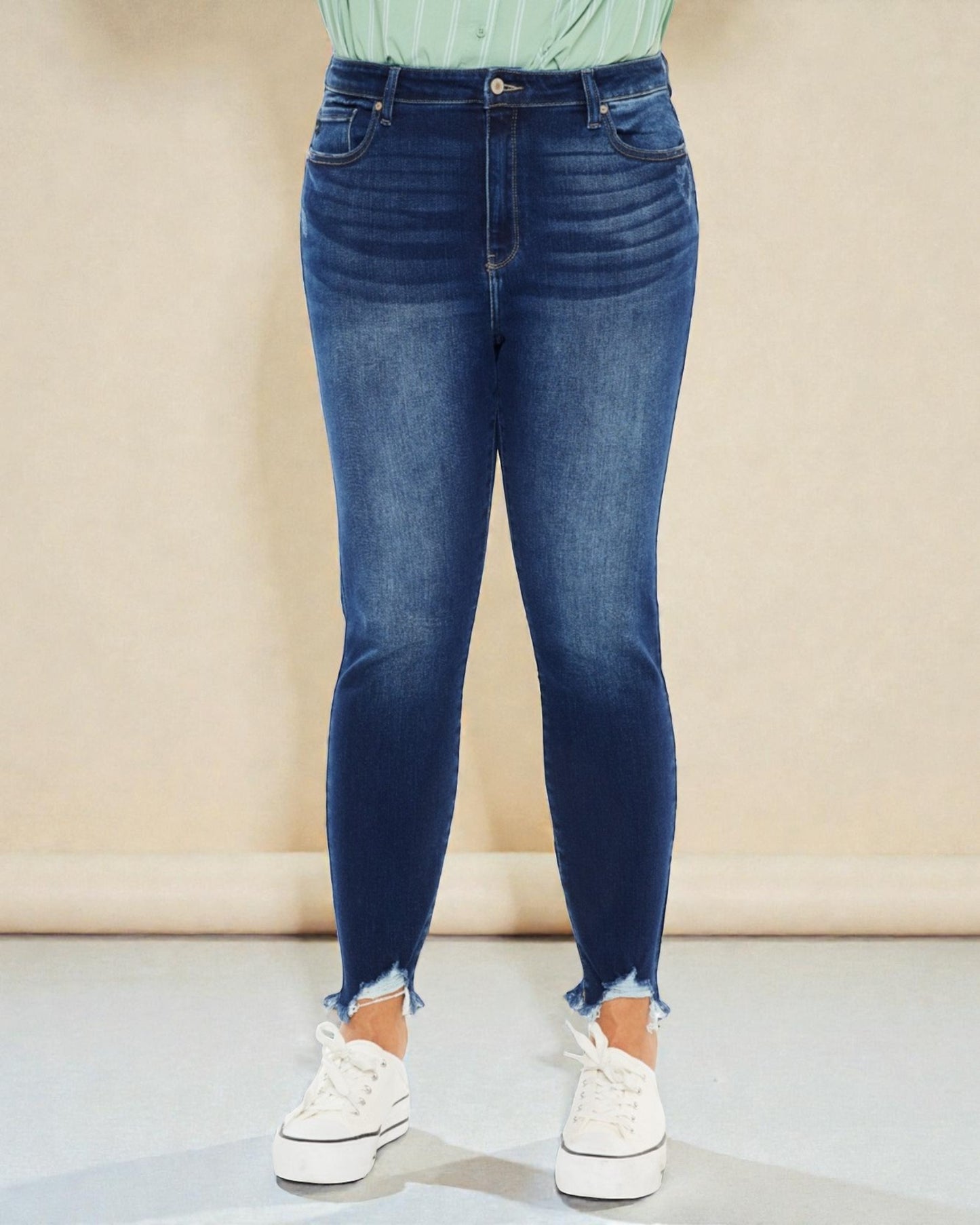 Person wearing blue jeans and white sneakers on a neutral background