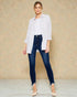 Woman wearing a white shirt and blue jeans against a beige background