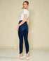 Woman wearing blue jeans and a white top against a beige background
