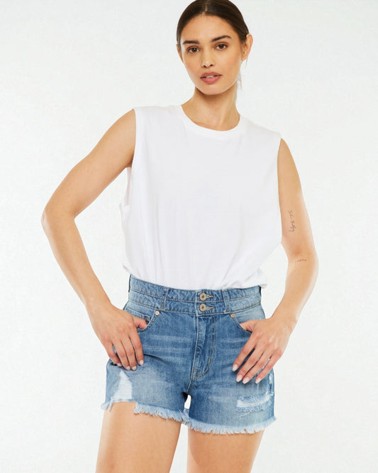 Woman wearing a white sleeveless top and denim shorts on a white background