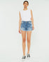 Woman wearing a white sleeveless top and denim shorts on a white background