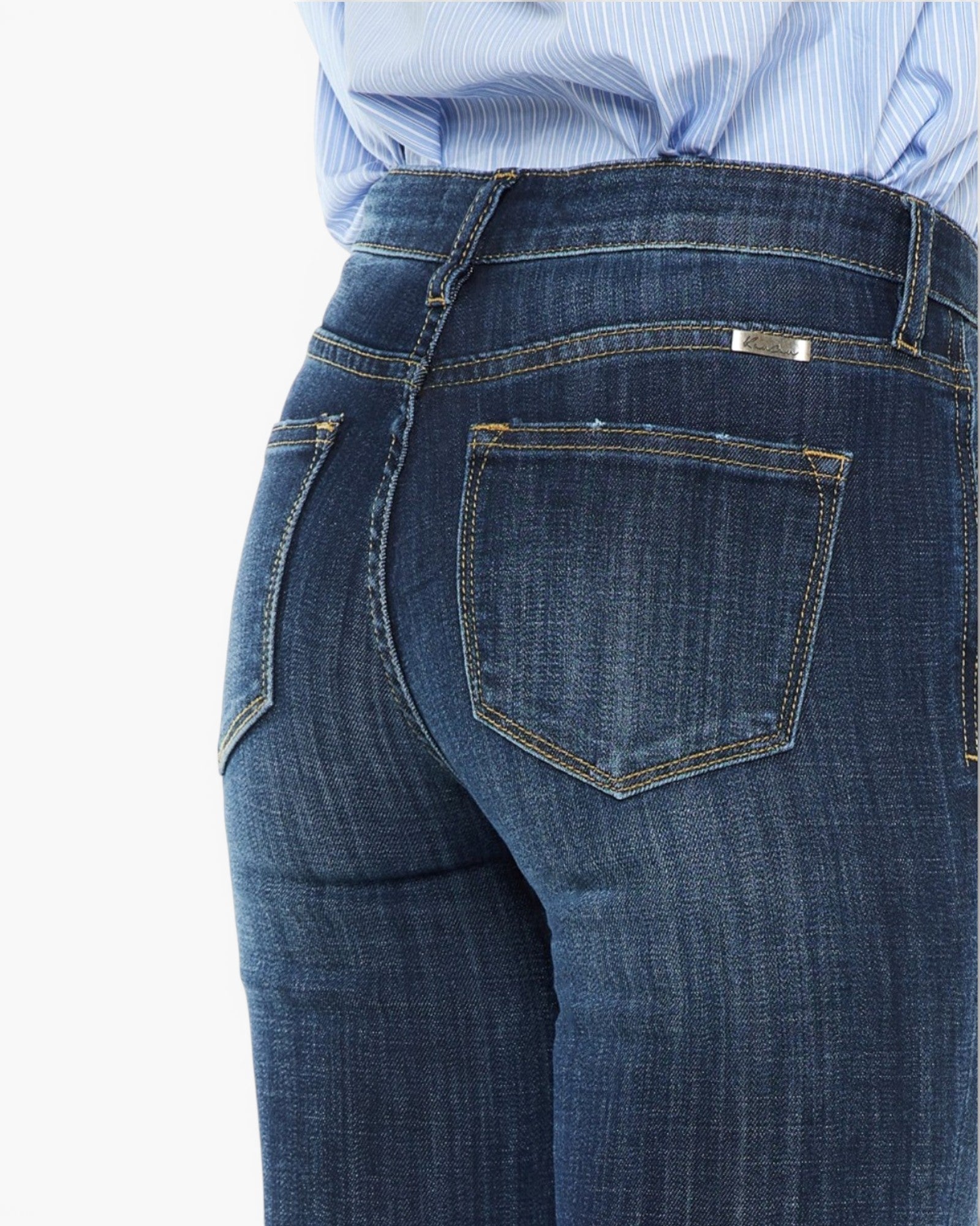 Close-up back view of a person wearing dark blue denim jeans with a light blue and white striped shirt tucked in, against a plain white background.