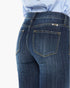 Close-up back view of a person wearing dark blue denim jeans with a light blue and white striped shirt tucked in, against a plain white background.