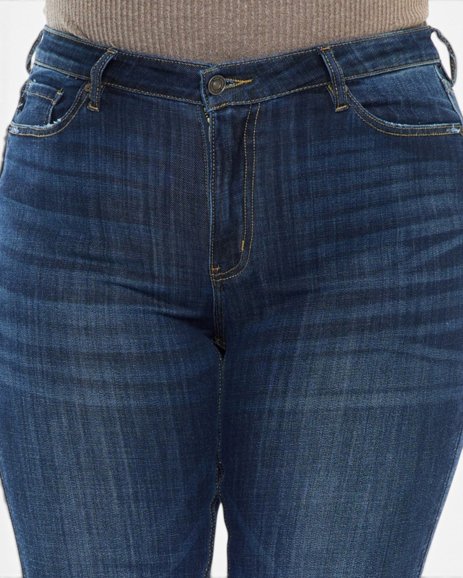 Close-up of a person wearing dark blue denim jeans with a ribbed beige top visible at the waistband.