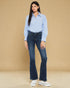 Woman wearing a light blue shirt and dark blue jeans against a beige background