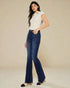 Woman wearing a white top and blue jeans on a beige background