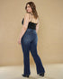 Woman wearing blue jeans and a black top against a beige background