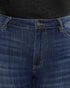 Close-up of dark blue denim jeans showing the front waistband, button closure, belt loops, and contrast stitching.