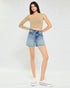 Woman wearing a beige crop top and denim shorts on a white background
