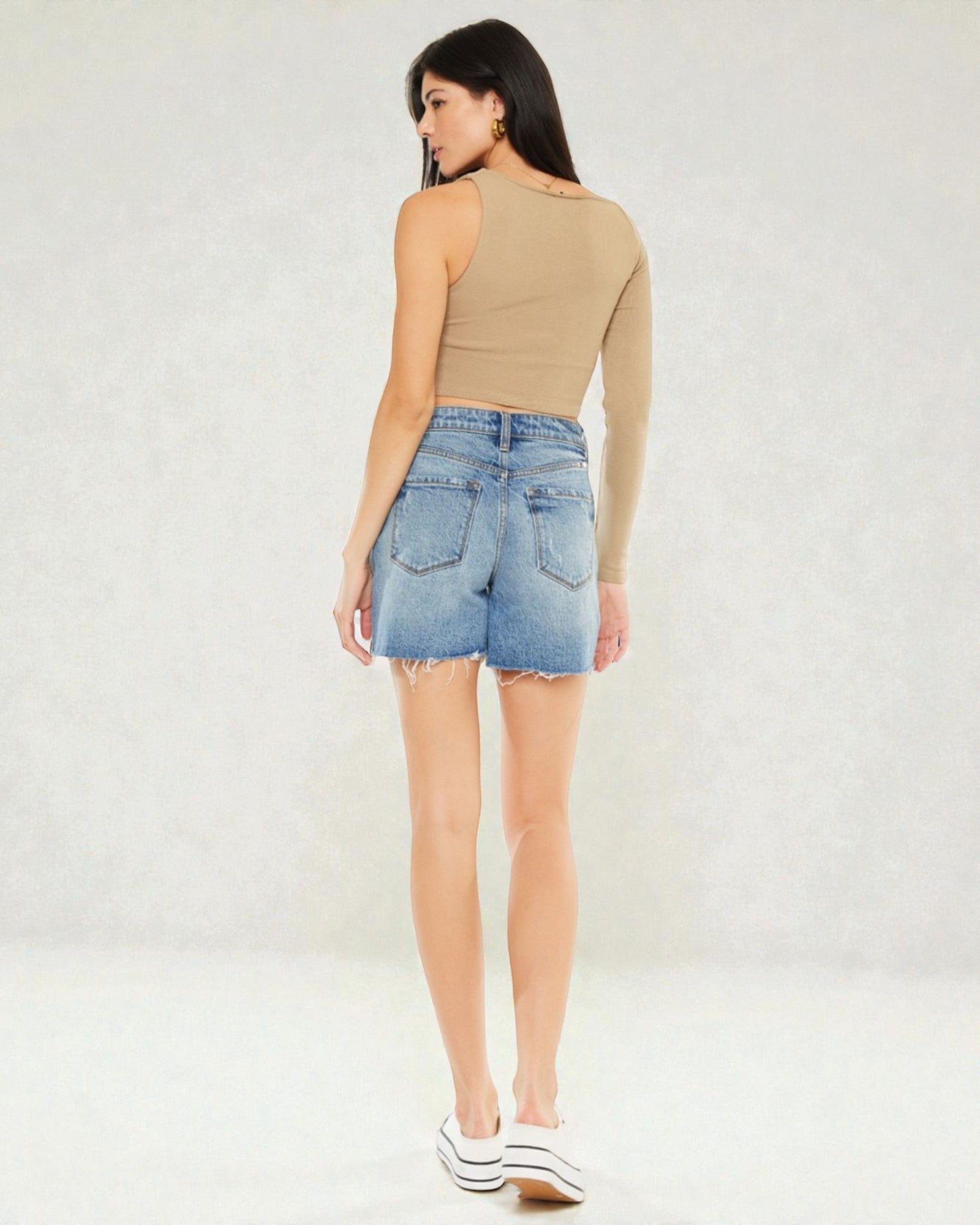 Woman wearing a beige top and denim shorts on a white background