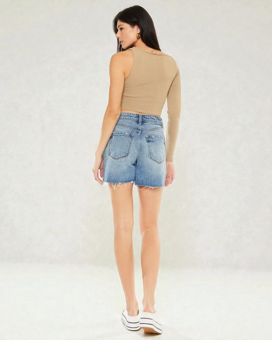 Woman wearing a beige top and denim shorts on a white background