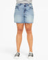 A person wearing light-wash blue denim shorts with a frayed hem, paired with a black-and-white striped top and black low-top sneakers, shown against a plain light gray studio background.