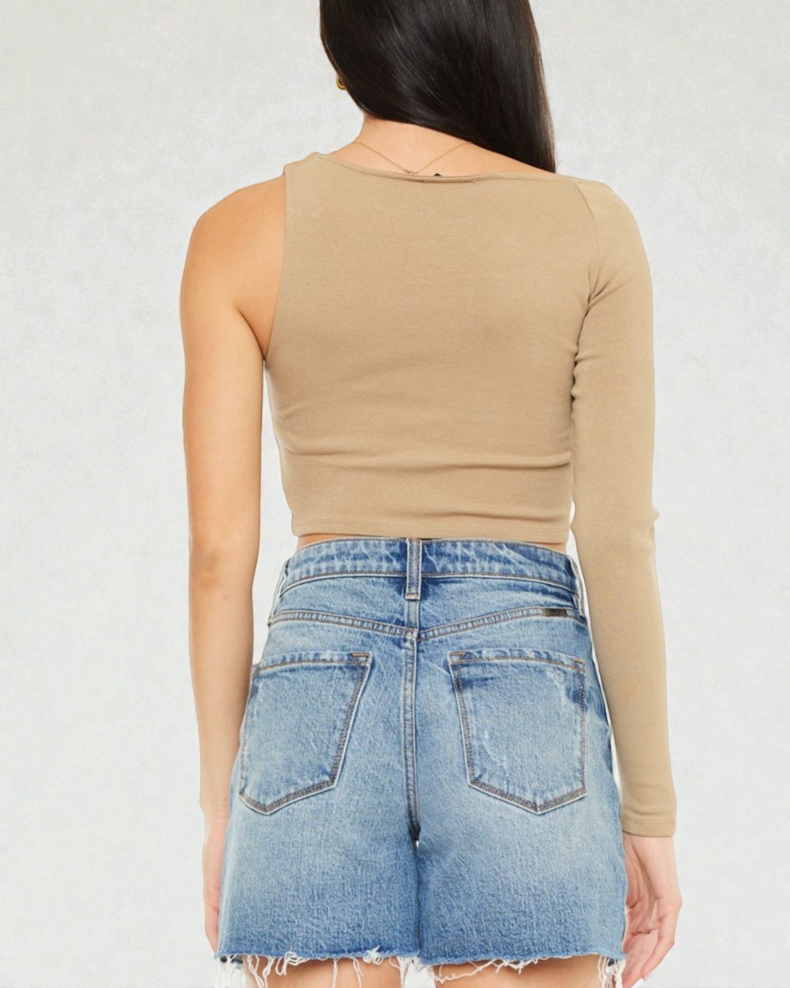 Person wearing a beige long-sleeve crop top and denim shorts on a white background