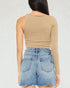 Person wearing a beige long-sleeve crop top and denim shorts on a white background