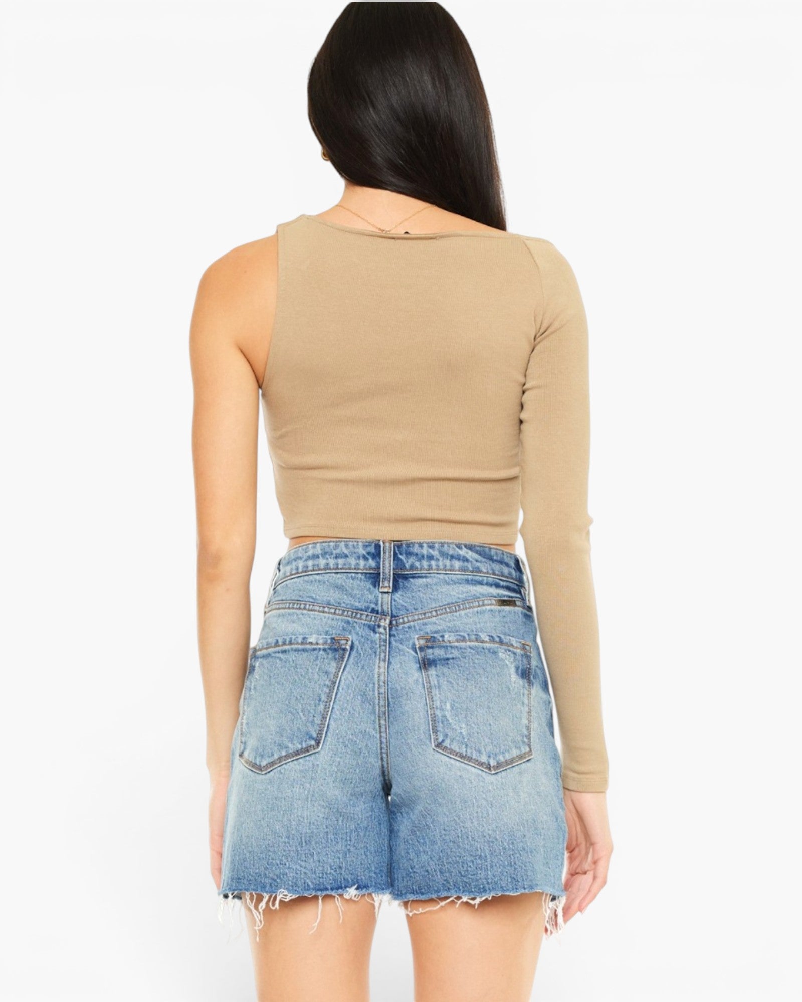 A woman shown from the back wearing a beige long-sleeve crop top and light blue denim shorts against a plain white background.