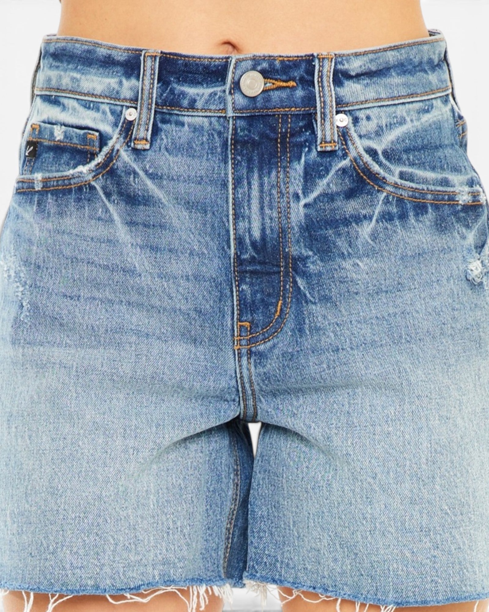Close-up of a person wearing light blue high-waisted denim shorts with a raw frayed hem and distressed fading.