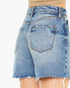 Close-up back view of light blue denim shorts with a frayed hem, shown on a model against a plain white background.