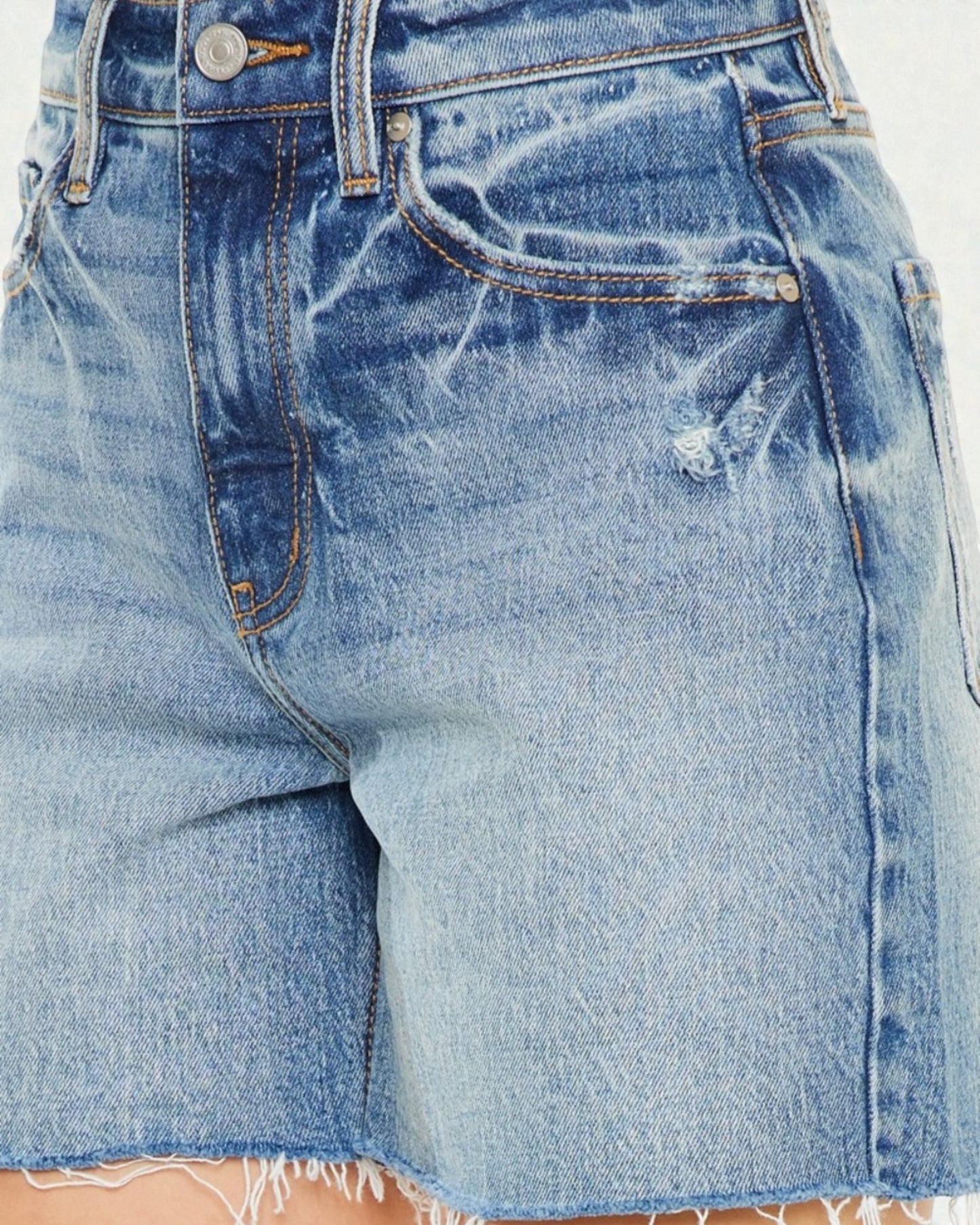 Close-up of a pair of blue denim shorts with visible distressing.