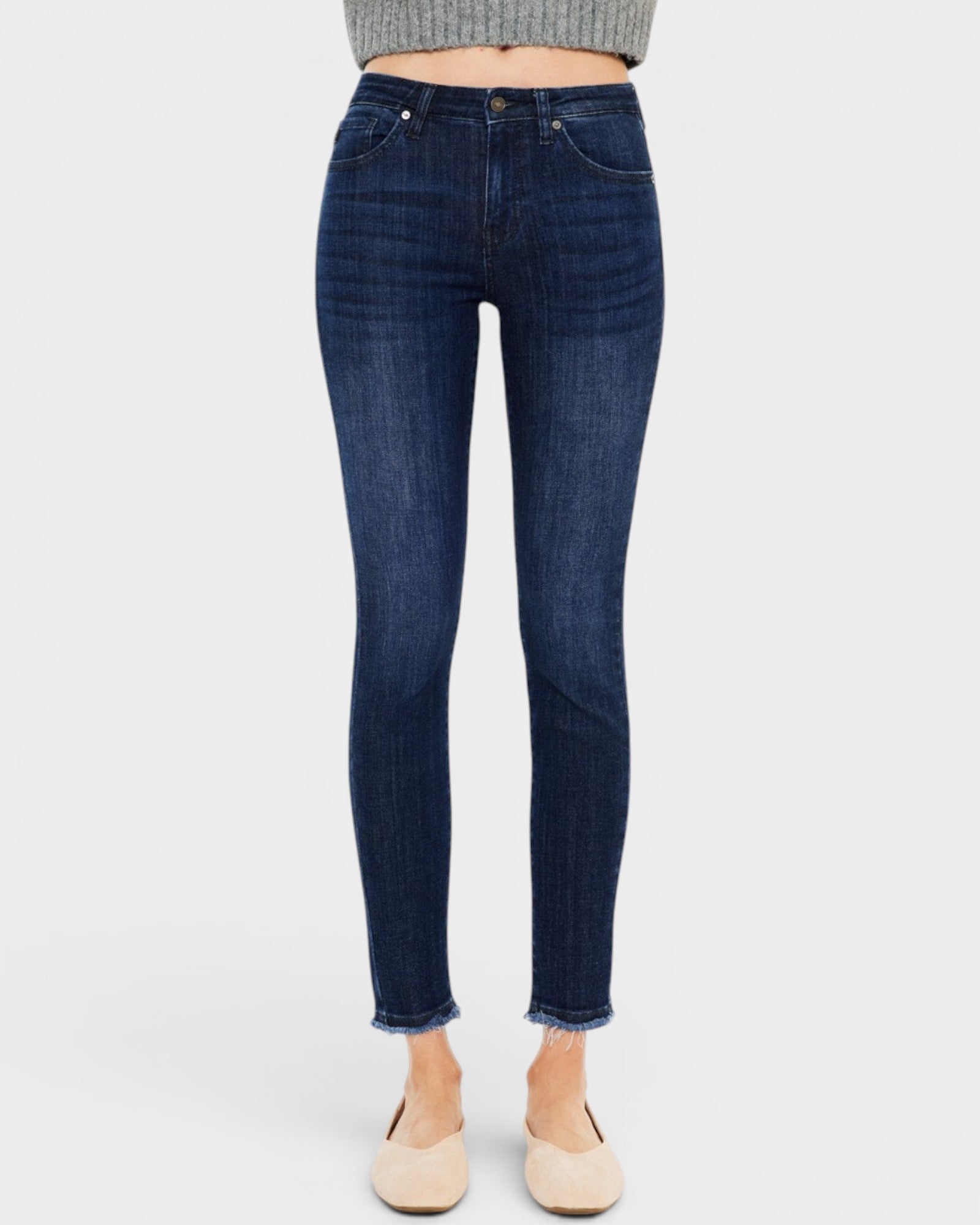 Dark blue jeans worn by a person on a white background