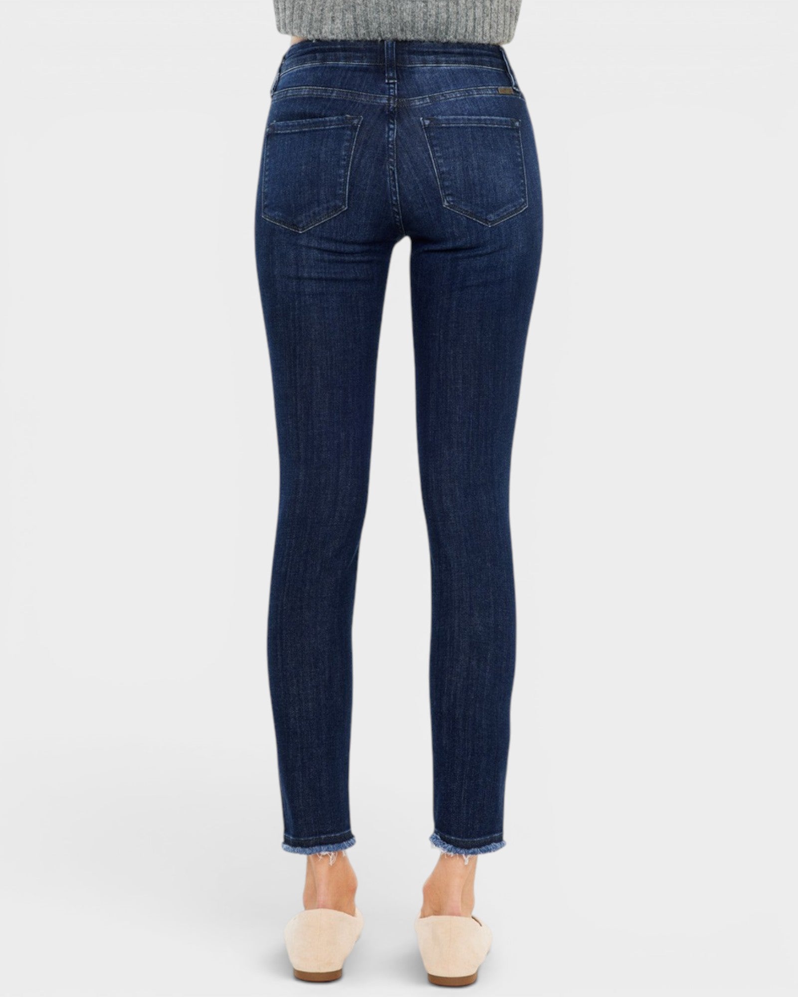 Dark blue jeans worn by a person on a white background