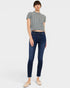 Woman wearing a gray sweater and dark blue jeans on a white background