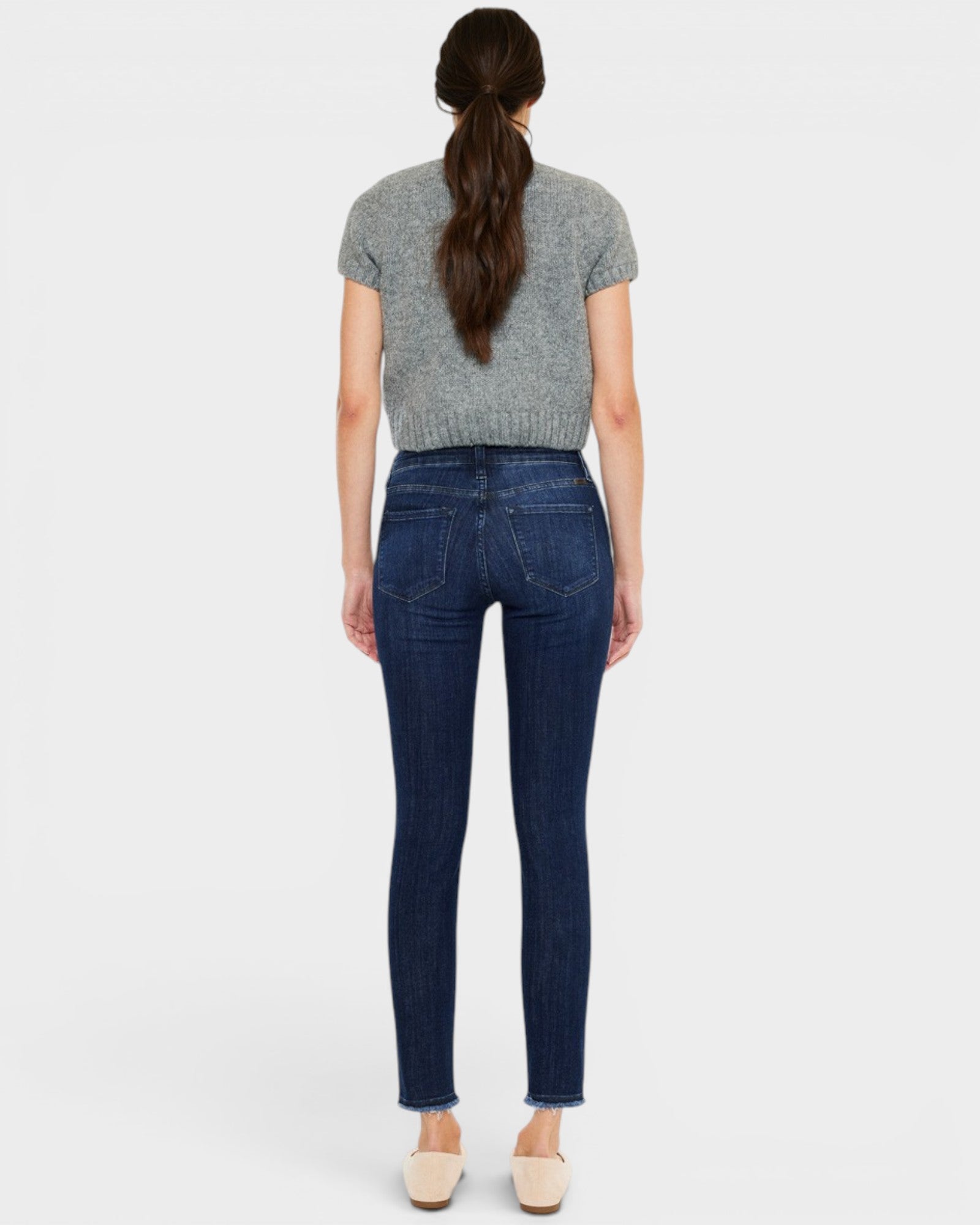 Woman wearing blue jeans and a gray top on a white background