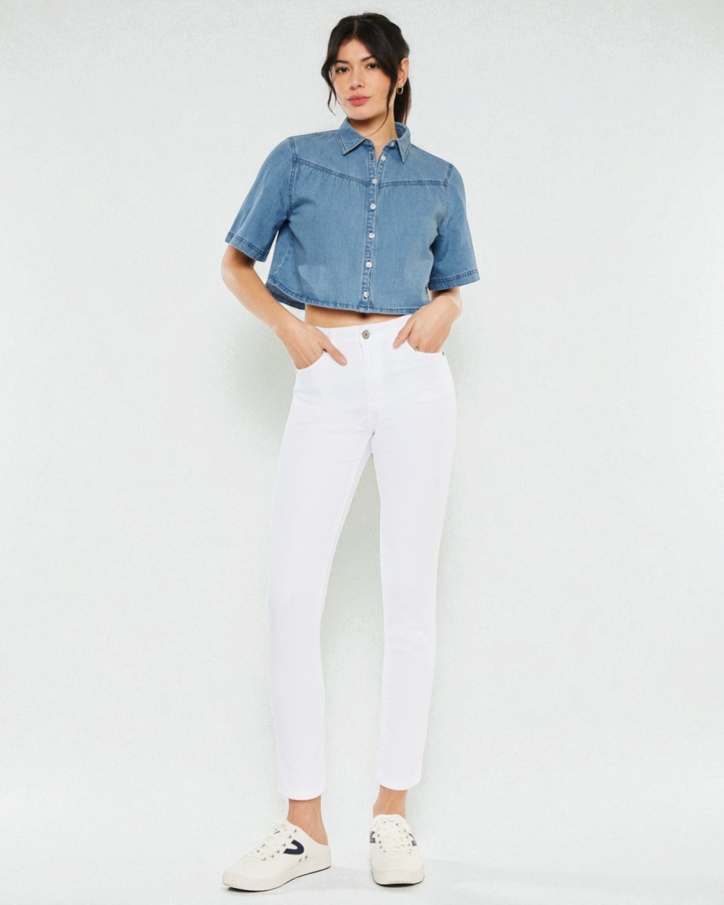 Woman wearing a denim shirt and white pants on a white background