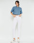 Woman wearing a denim shirt and white pants on a white background
