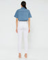 Person wearing a denim shirt and white pants on a plain background