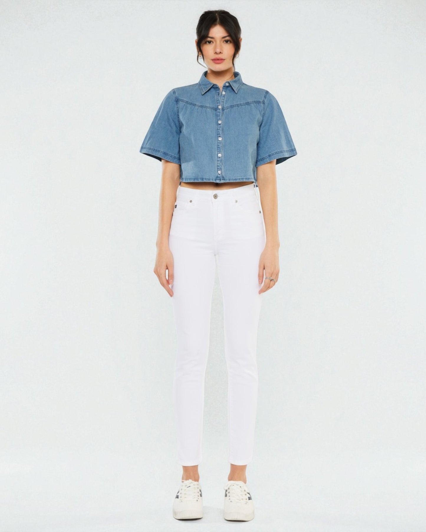 Person wearing a denim shirt and white pants on a plain background