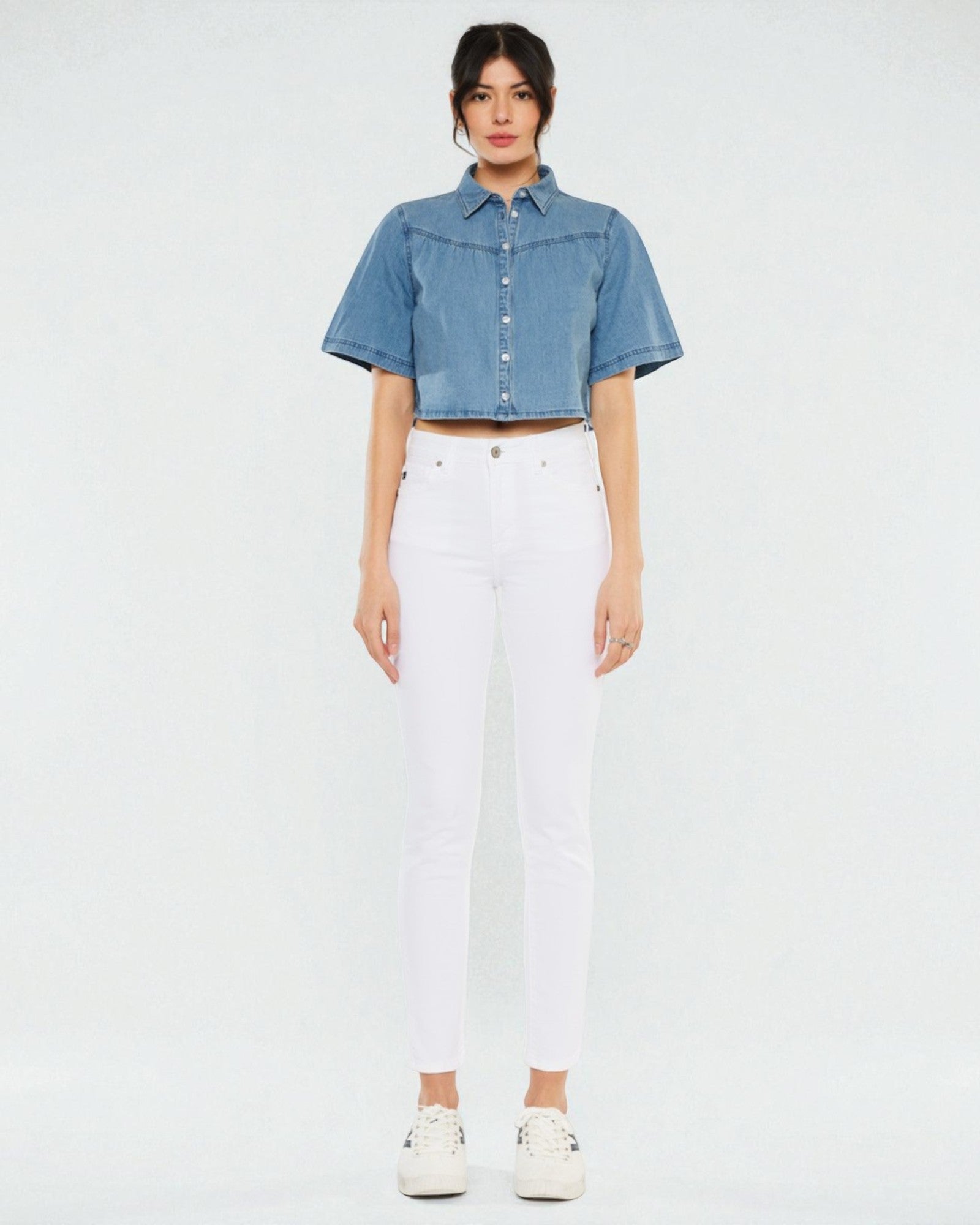 Person wearing a denim shirt and white pants on a plain background